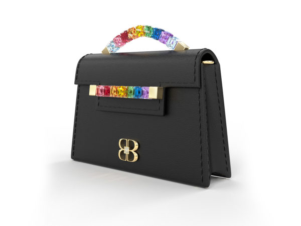 Front side angle view of black Rainbow Baby Jewel Crossbody showing a slender, collapsible side profile. Emerald-cut Swarovski crystals are flush together at their edges, forming a rainbow gradient with square-shaped yellow gold hardware end caps.